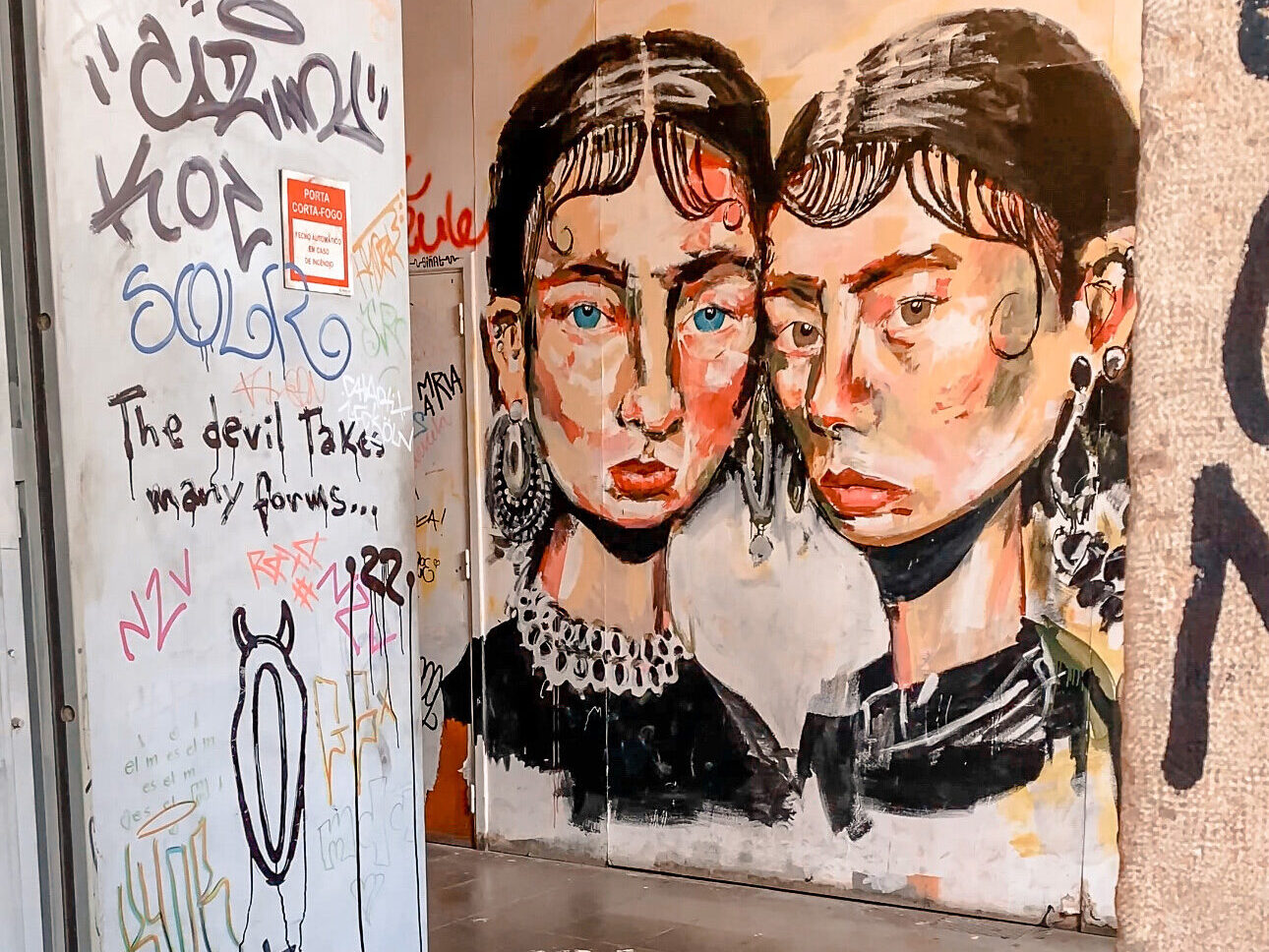Graffiti art in LX Factory warehouse. Two spray painted female faces with text.
