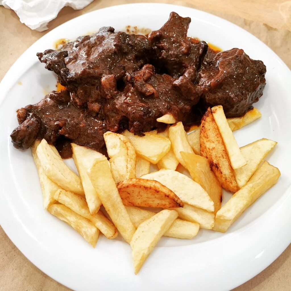 Andalusian dish of rabo de taro served with french fries on white plate