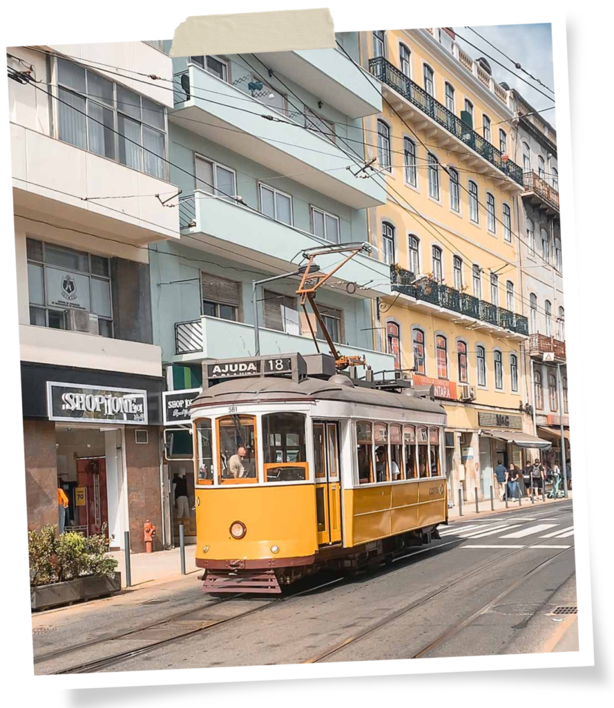 The historic yellow tram passes blue and yellow buildings in Lisbon.