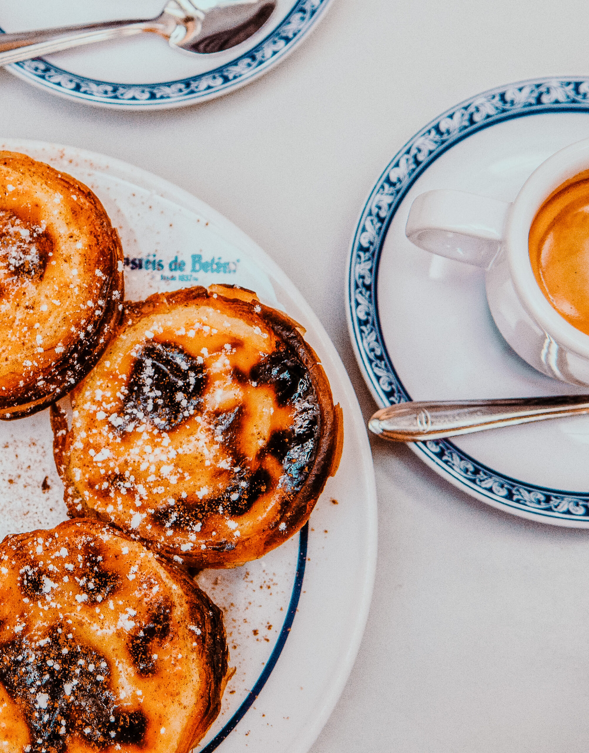 Plate of pastel de nata with powdered sugar on top.