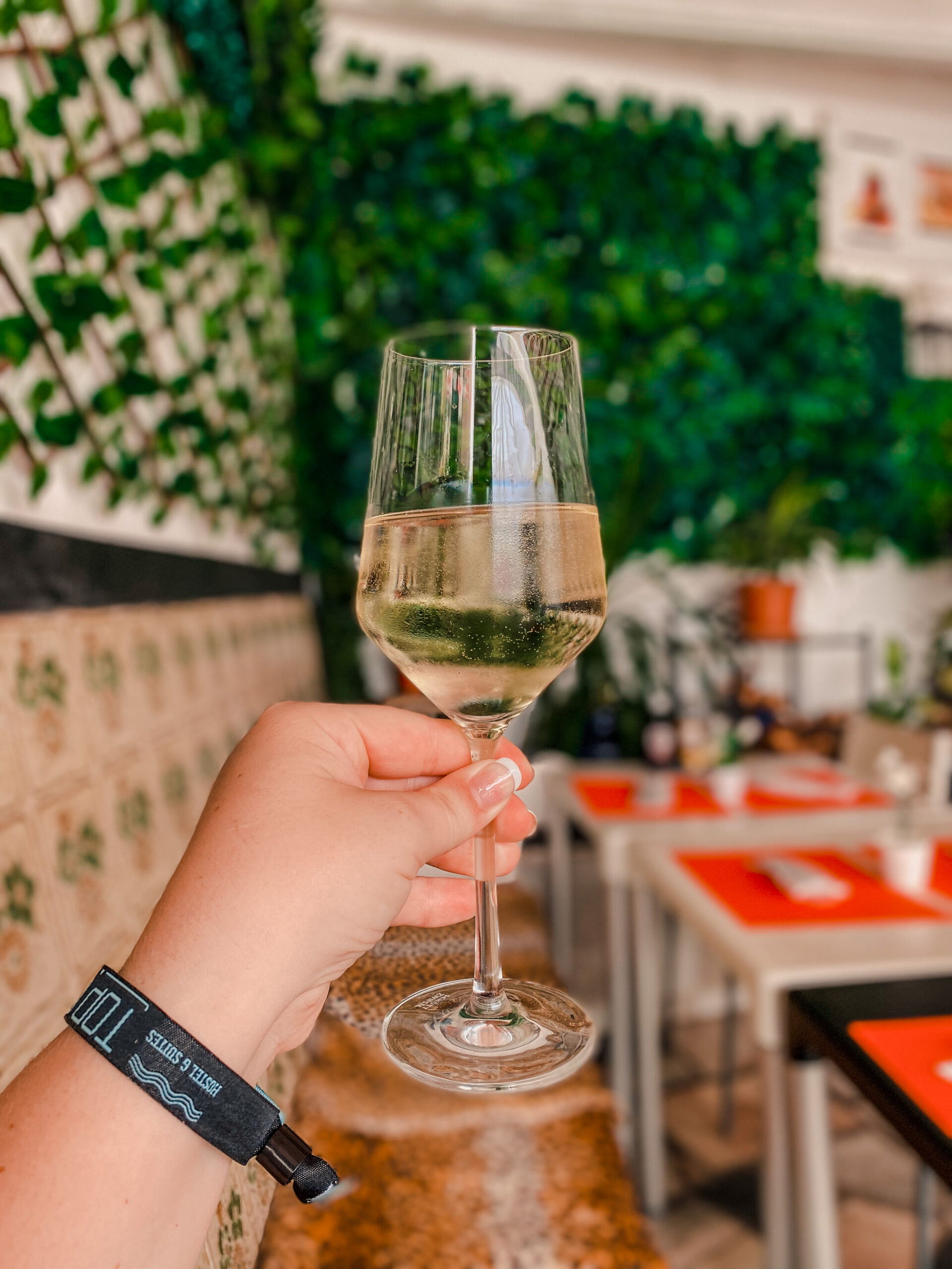 A solo traveler holds a glass of vinho verde at a restaurant in Portugal.