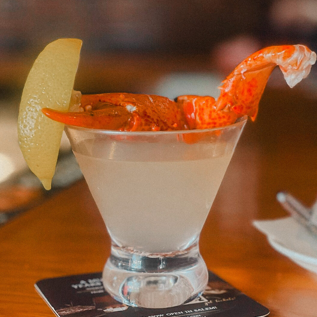 martini with lobster claw and lemon garnish