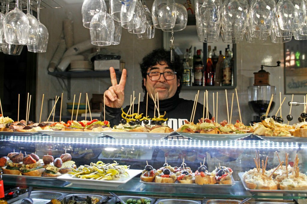 waiter at a spanish tapas bar greeting tour customers