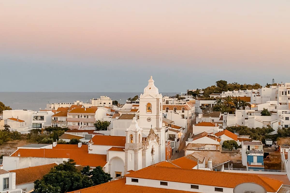 A gorgeous sunset over the white buildings and red tiled roofs of the Algarve coast.