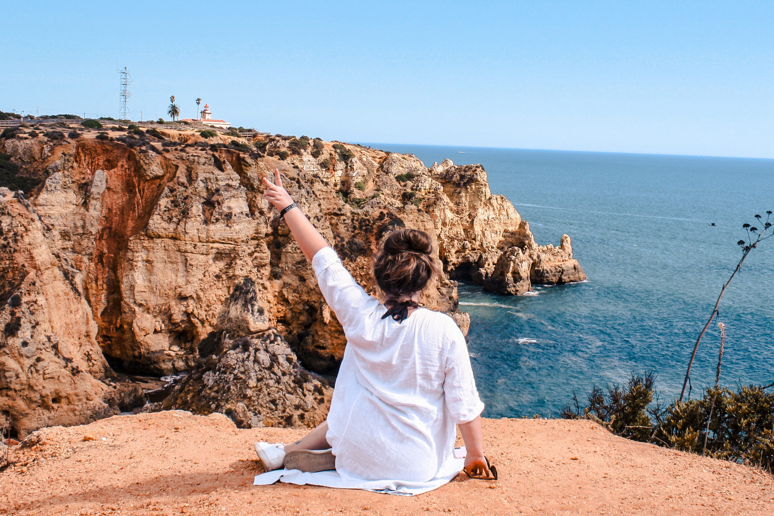 Solo traveler exploring Algarve's coast and giving a peace sign.