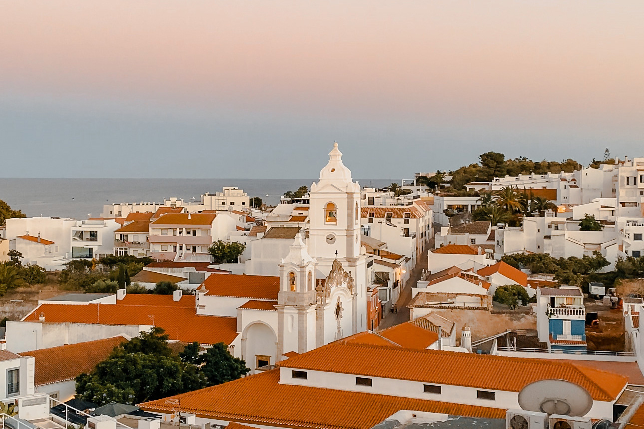 A gorgeous sunset over the white buildings and red tiled roofs of the Algarve coast.