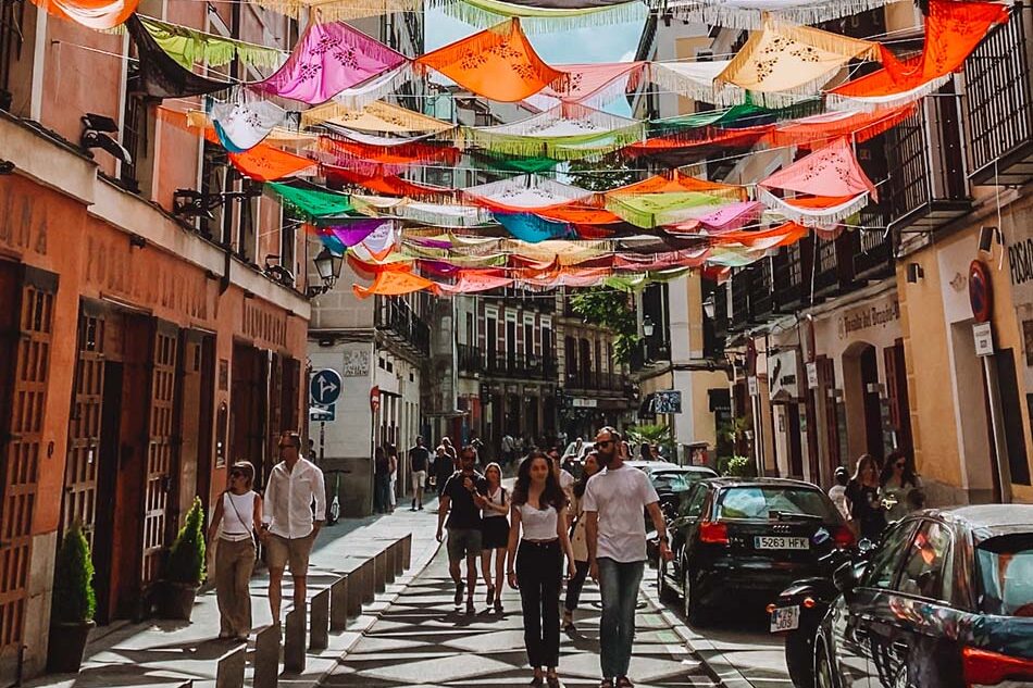 view of calle cava baja with colorful spanish flags covering street in madrid